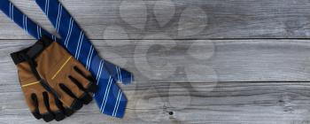 Blue striped necktie with work gloves on aged wooden planks for Happy Fathers Day concept