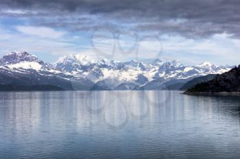 Close up of Alaska Glacier bay during summer time. Clouds and blue sky mixed among the mountains. 