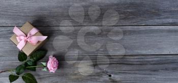 Single pink rose with gift box  over weathered wooden planks for Mothers day love holiday concept background
