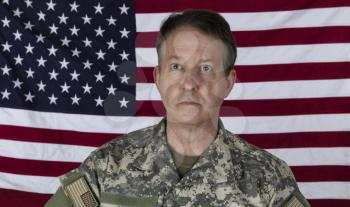 Mature man wearing military outer shirt without cap with US flag in background 