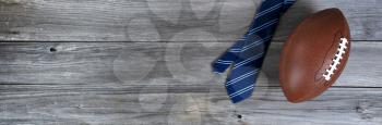 Blue striped necktie and a football on weathered wooden planks for Happy Fathers Day concept 