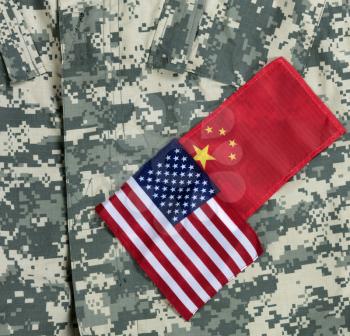 US and China flags on military uniform background for trade war concept 