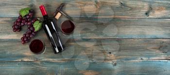Red wine background with bottle, drinking glasses, grapes and vintage corkscrew on faded blue wood planks