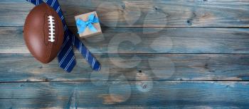 Football, neck tie and giftbox on faded blue wood for happy fathers day concept background 