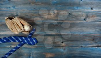 Old baseball glove, ball and neck tie on faded blue wood for happy fathers day concept background 