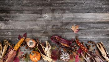 Autumn border with faded leaves, pumpkins, acorn and corn on vintage wooden planks 