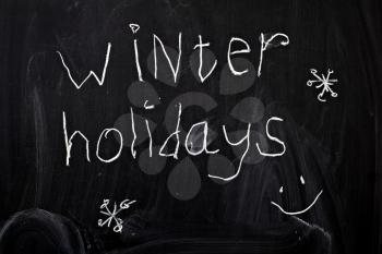 Inscription winter holidays, written by a child's hand on the chalk board