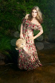 Beautiful girl in the national dress and hat stand in the river in the  forest