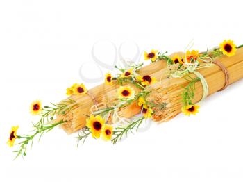 Uncooked Italian spaghetti decorated with yellow flowers isolate on white background, selective focus