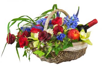 Flower arrangement of roses, orchids, fruits and bottle of wine in basket isolated on white background. Closeup.