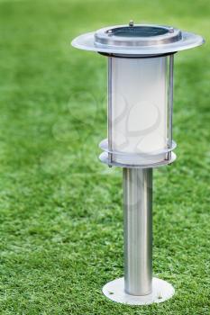 Solar-powered lamp on green grass background. Selective focus.