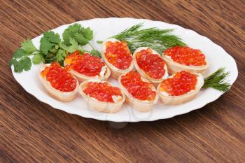 Tartlets with red caviar on wooden background. Closeup.