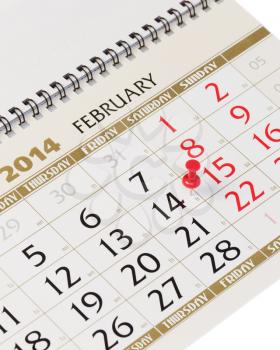 Calendar page with red thumbtack on February 14 2014. Closeup.