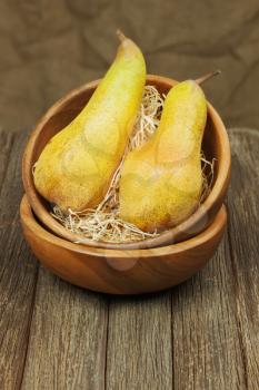 Ripe pears in bowl on wooden background. Closeup.