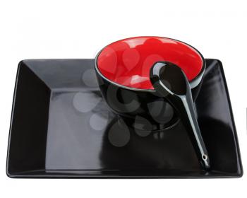Black ceramic bowl and spoon on tray isolated on white background. Closeup.