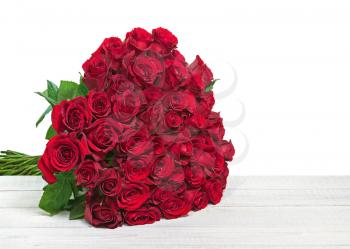 Colorful flower bouquet from red roses isolated on wooden background. Closeup.