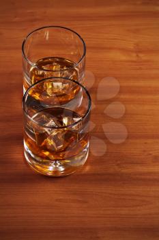 Highball whiskey glass with ice on wooden background. Closeup.