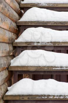 Powdery snow covered old wooden stairs. Abstract winter background composition.
