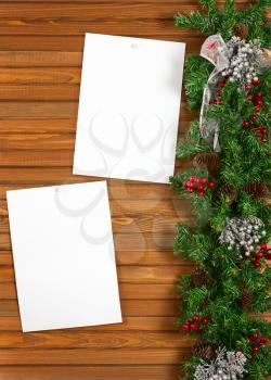 Garland with Christmas ornaments, pine cones and sheets of paper on wooden background.