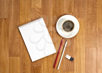 Blank notepad with office supplies and cup of coffee on wooden table. Above view.