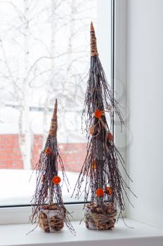 Abstract Christmas trees from natural materials standing on the windowsill. Manual design work.