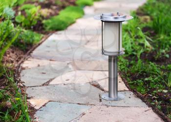 Solar-powered lamp on garden path. Nature background. Selective focus.