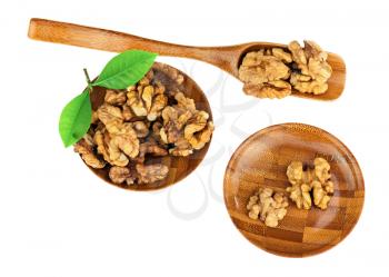 Handful of walnuts in wooden bowls, scoop and green leaves isolated on white background. Closeup. Selective focus.
