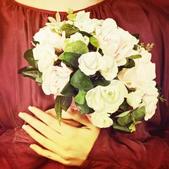 Beautiful wedding bouquet from white and pink roses in hands of bride with retro filter effect.