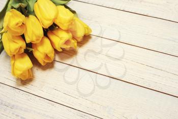 Fresh yellow tulips on wooden background. Holiday background. Top view. Photo with retro filter effect.