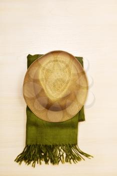 Straw hat and green scarf in hipster style on wooden background. 