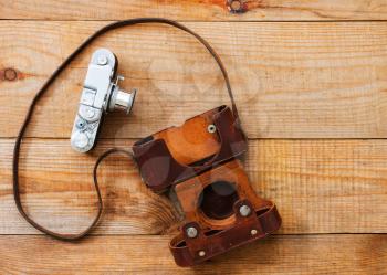 Vintage, very old film camera on brown wooden background and space for text.