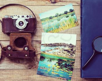 Vintage, very old film camera, magnifying glass, foto and photo album on brown wooden background and space for text. Photo with retro filter effect.
