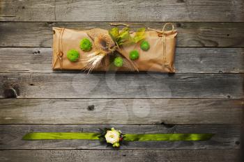 Handmade gift and bracelet on the arm decorated with natural flowers, ears of wheat and elements on dark wooden background.