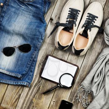 Set of travel items including scarf, sunglasses, sneakers, note book, magnifying glass, mobile phone and jeans. Overhead view. Flat lay.