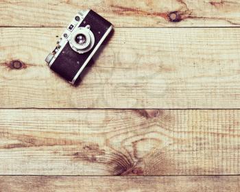 Vintage, very old film camera on brown wooden background and space for text. Photo with retro filter effect.
