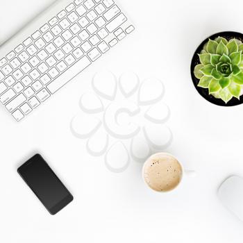 White office desk table with wireless aluminum keyboard, cup of coffee, smart phone with black screen, mouse and succulent flower in pot. Top view with copy space. Flat lay. 