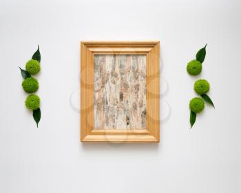 Wooden frame with collage of birch bark with decoration of chrysanthemum flowers and ficus leaves on white background. Overhead view. Flat lay.