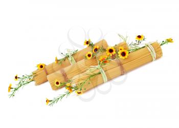 Uncooked Italian spaghetti decorated with yellow flowers isolated on white background.