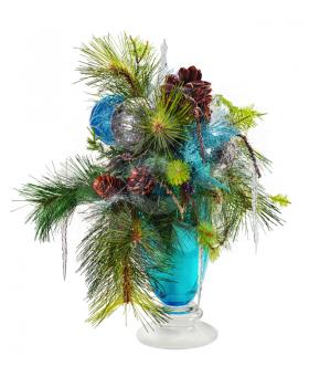Christmas arrangement of Christmas balls, snowflakes, candles, beads and pine branches in blue vase isolated on white background.