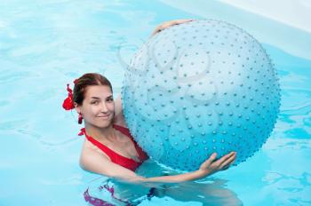 Young beautiful girl with blue ball in swimming pool. 