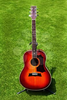 Acoustic guitar on background of green grass. Closeup.