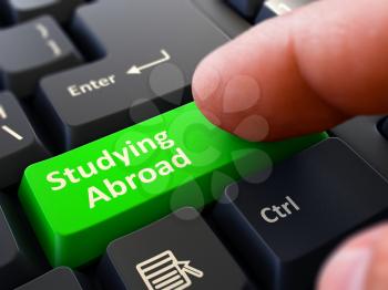 Studying Abroad Button. Male Finger Clicks on Green Button on Black Keyboard. Closeup View. Blurred Background. 3D Render.