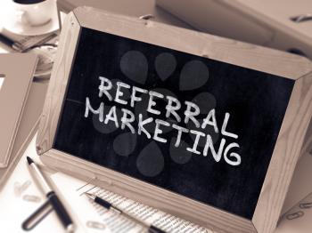 Referral Marketing Handwritten on Chalkboard. Composition with Small Chalkboard on Background of Working Table with Office Folders, Stationery, Reports. Blurred, Toned Image. 3D Render.