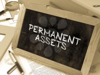 Permanent Assets - Chalkboard with Hand Drawn Text, Stack of Office Folders, Stationery, Reports on Blurred Background. Toned Image. 3D Render.