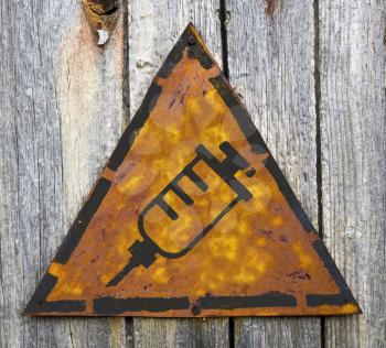Royalty Free Photo of a Syringe on a Rustic Sign Hanging on Wood