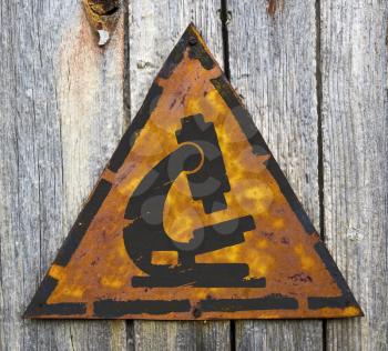 Royalty Free Photo of a Microscope on Rusty Sign on a Wooden Wall