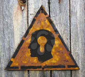 Royalty Free Photo of a Head With a Keyhole on a Rusty Sign Against a Wooden Wall