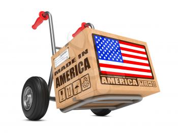 Cardboard Box with Flag of USA and Made in America Slogan on Hand Truck White Background. Free Shipping Concept.