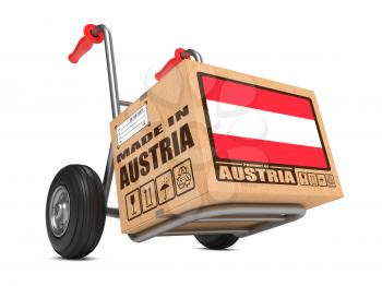 Cardboard Box with Flag of Austria and Made in Austria Slogan on Hand Truck White Background. Free Shipping Concept.