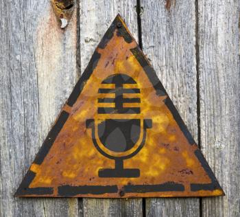 Royalty Free Photo of a Microphone on a Yellow Warning Sign on Wood